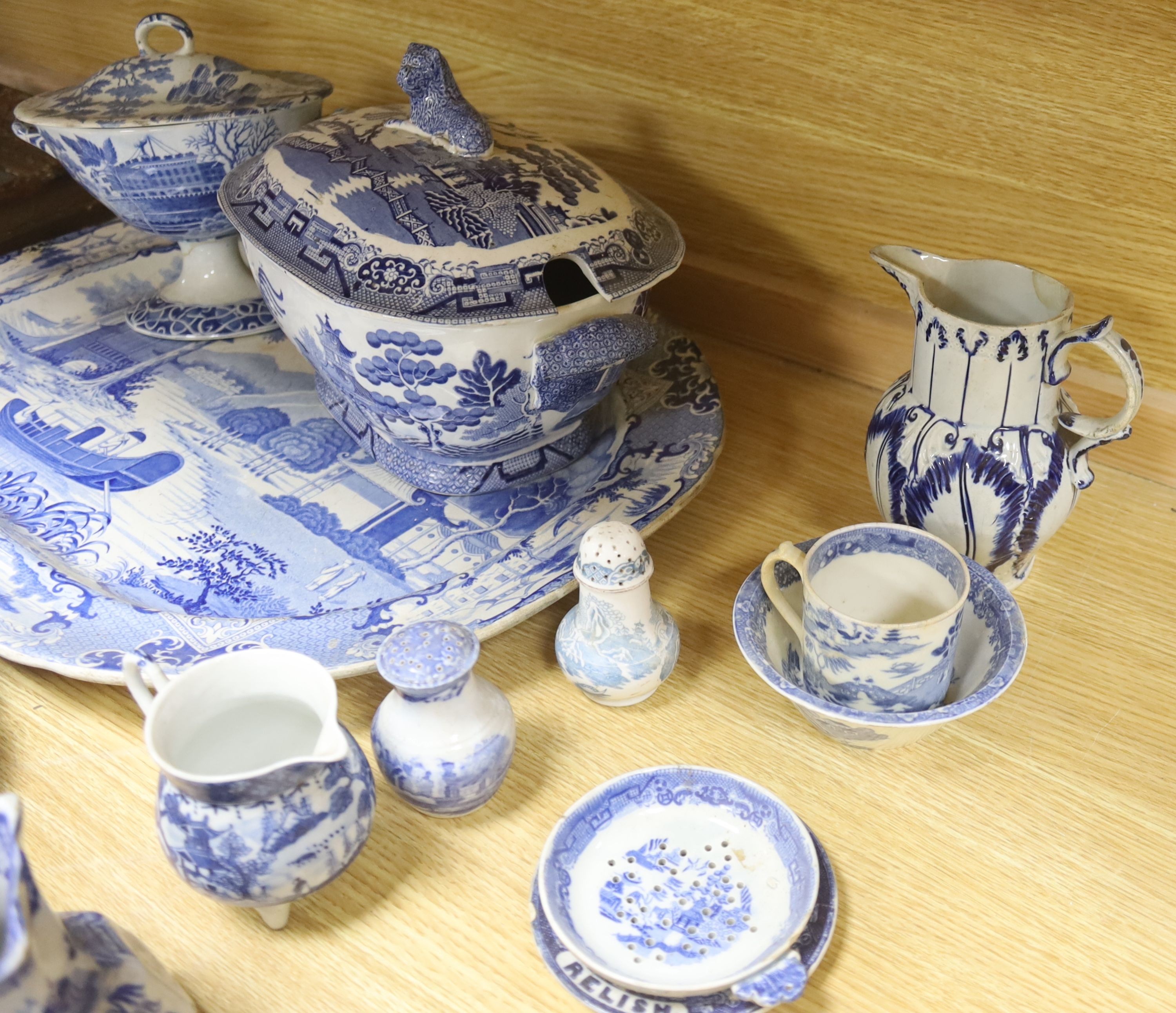 A group of 19th century blue and white pottery to include a chinoiserie pattern meat plate, 53.5 cm, a patent ironstone pheasant pattern dish, 47.5 cm, various tureens, dishes, ladles etc. a pearlware jug and two Chinese
